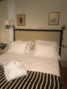 1 cama grande con sábanas y almohadas blancas en Albergo Le Casaline, en Campello sul Clitunno