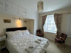 um quarto com uma cama, 2 cadeiras e uma janela em The Durbeyfield Guest House em West Bay