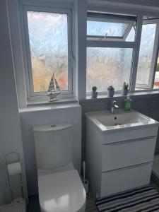 a bathroom with a toilet and a sink and a window at II comfortable room, Shared House in Bristol