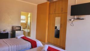 a bedroom with two beds and a flat screen tv at Pab-Love Guest House in Kuruman
