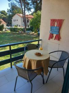 a table and chairs on a balcony with a glass of wine at Apartmani LUNI in Premantura