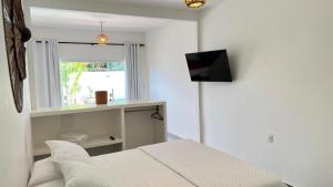 a bedroom with a bed and a television on a wall at Aki Pousada in São Miguel do Gostoso