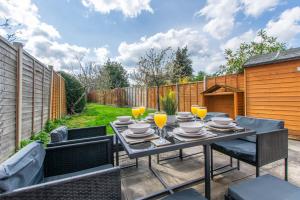 een patio met een tafel met stoelen en drankjes bij One Harp Hill in Cheltenham