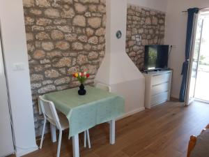 a dining room with a table with a vase of flowers on it at Apartmani LUNI in Premantura