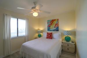 a bedroom with a white bed and a ceiling fan at 33C Lighthouse Point in Tybee Island