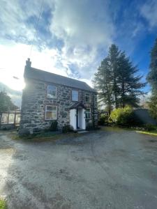 a stone house with a driveway in front of it at Rhydydefaid Bed and Breakfast, Guesthouse in Frongoch, Snowdonia in Frongoch