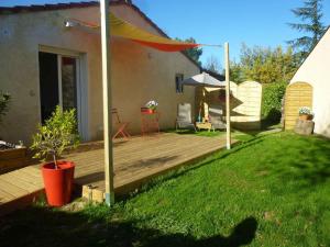 un patio trasero con terraza de madera y sombrilla en Chambre d'hôtes "Mirabel", en Saint Jean