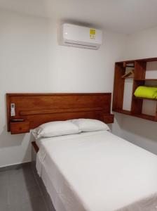 een slaapkamer met een wit bed en een houten hoofdeinde bij HOTEL SAN ADOLFO in Apartadó