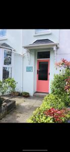 una puerta roja en un edificio blanco con un cartel en él en The Shell House en Falmouth