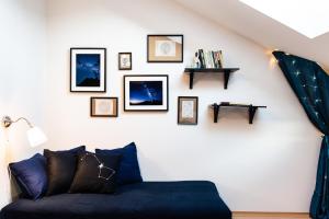 a living room with a blue couch and pictures on the wall at Night Sky Studio - Brno in Brno