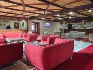 a waiting room with red chairs and a table at Hotel Meteorites Boulaajoul in Zaida