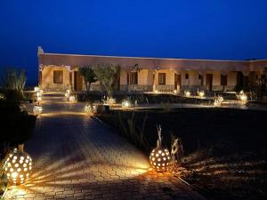 a building with lights in a courtyard at night at Hotel Meteorites Boulaajoul in Zaida