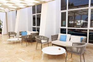 Hotel Riad Meninx Djerba في Djerba: غرفة معيشة مع كراسي وأريكة وطاولات