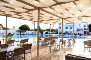 Hotel Riad Meninx Djerba في Djerba: فناء به طاولات وكراسي ومسبح