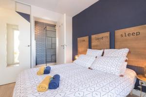sypialnia z dużym białym łóżkiem i niebieskimi poduszkami w obiekcie Le Bleu Nuit Piscine Parking Netflix Café w mieście Villemur-sur-Tarn