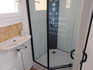 una ducha con una puerta de cristal junto a un lavabo en centre historique et proche mer, en Sigean