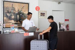 dos hombres parados en una caja registradora con una maleta en Hotel Boutique Trinidad, en Viña del Mar