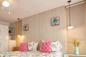 a bedroom with a bed with pink and green pillows at Casa Congo & Casa Rayo Verde - Restaurante - Galeria de arte in Portobelo