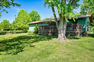 a green house with a tree in the yard at 2 Mins to Pkwy & Strip - Modern Pigeon Forge Gem Near Gatlinburg & Smokies in Pigeon Forge