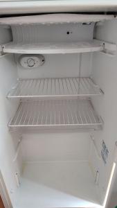 um frigorífico vazio com a sua porta aberta e prateleiras vazias em Apartamento(1) inteiro com sala reversivel em Volta Redonda