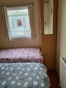 a small bedroom with a bed and a window at Beautiful Caravan in Ingoldmells