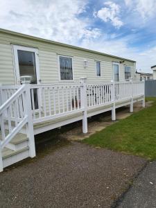 a white house with a porch and a white fence at Beautiful Caravan in Ingoldmells