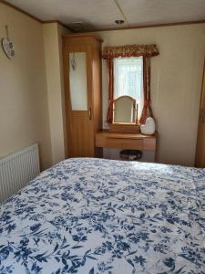a bedroom with a blue and white bed and a mirror at Beautiful Caravan in Ingoldmells