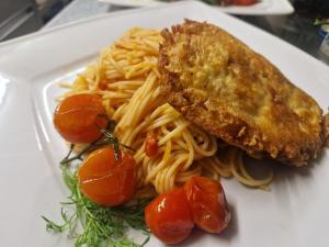 a white plate of pasta with a piece of fish and tomatoes at Landgasthaus "Zum Engel" in Neuleiningen