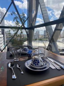 een tafel met borden en keukengerei op een tafel met een raam bij Hotel Black Inn Flamboyant in Goiânia