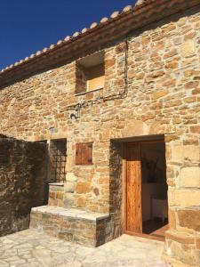 un edificio de ladrillo con puerta de madera y ventana en Masia Campos Culla, en Culla