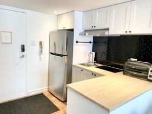 a kitchen with white cabinets and a stainless steel refrigerator at Loft LaprèSKI, Lit king, sauna/piscine et montagne in Saint-Férréol-les-Neiges