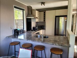 a kitchen with three bar stools and a sink at Even Closer to the Forest in Rotorua