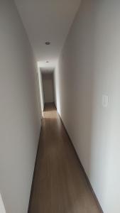 an empty hallway with white walls and a wooden floor at Apt(2) no centro de VR tudo perto até 7 pessoas in Volta Redonda