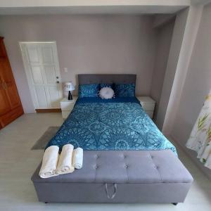 ein Schlafzimmer mit einem blauen Bett mit blauer Decke und weißen Handtüchern in der Unterkunft Miss Pea Apartments in Crown Point
