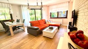 a living room with an orange couch and a table at Dolina Wikingów-apartament Suite z tarasem w ogrodzie, miejscem w garażu i dostępem do strefy wellness in Szklarska Poręba