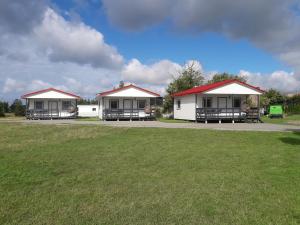 three white cottages with red roofs in a field at Domki pokoje pod Wierzba in Sarbinowo