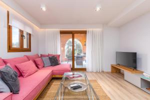 sala de estar con sofá rosa y TV en Lola's Luxury Apartments, en Liapades
