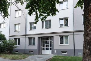 un edificio blanco con una puerta y un árbol en Tranquility Apartement - Brno, en Brno