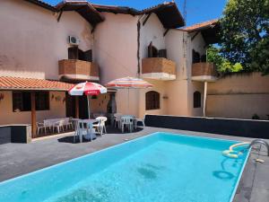 a swimming pool with chairs and umbrellas in front of a house at Casa Inteira Família próxima ao Santuário Nacional in Aparecida