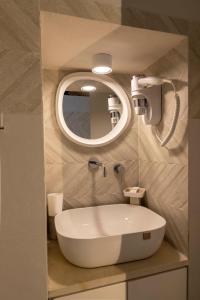 ein Badezimmer mit einem weißen Waschbecken und einem Spiegel in der Unterkunft Cà sotto l’arco in Ostuni