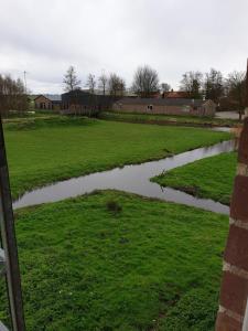 a river in a field next to a building at Landlust in Purmerend