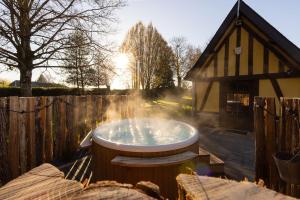 wanna z hydromasażem na dziedzińcu obok budynku w obiekcie Le Puits Jaune - Gîte Nature et Spa w mieście Saint-Denis-le-Thiboult