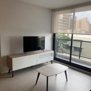 un soggiorno bianco con TV e sgabello di Pueyrredon 238 a Córdoba