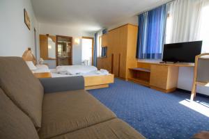 ナトゥルノにあるBad Kochenmoosのベッド1台、薄型テレビが備わるホテルルームです。