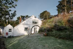 una casa blanca en una colina con un patio en Shilla Mill - Just off the Beach en Polzeath