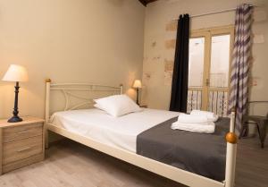 1 dormitorio con 1 cama con sábanas blancas y ventana en Iliotropio Art, en La Canea
