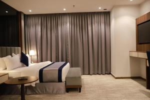 um quarto de hotel com uma cama e uma televisão em Tulip View Hotel em Khamis Mushayt