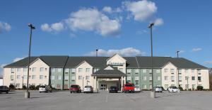 een groot gebouw met auto's geparkeerd op een parkeerplaats bij Greystone Inn & Suites in Vance