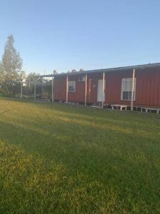 a row of red buildings in a field of grass at Casa Contenedor y espacio verde in Paysandú