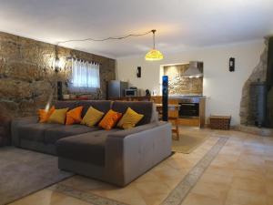 een woonkamer met een grijze bank met oranje kussens bij Casa dos Chãos in Cabeceiras de Basto